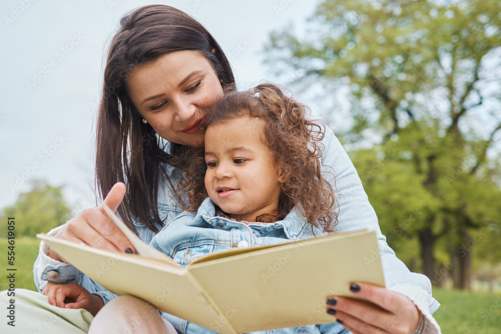 Mother and daughter reading together in the park